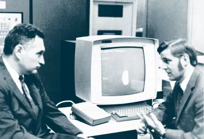 Two Men Sitting in Front of An Old Computer